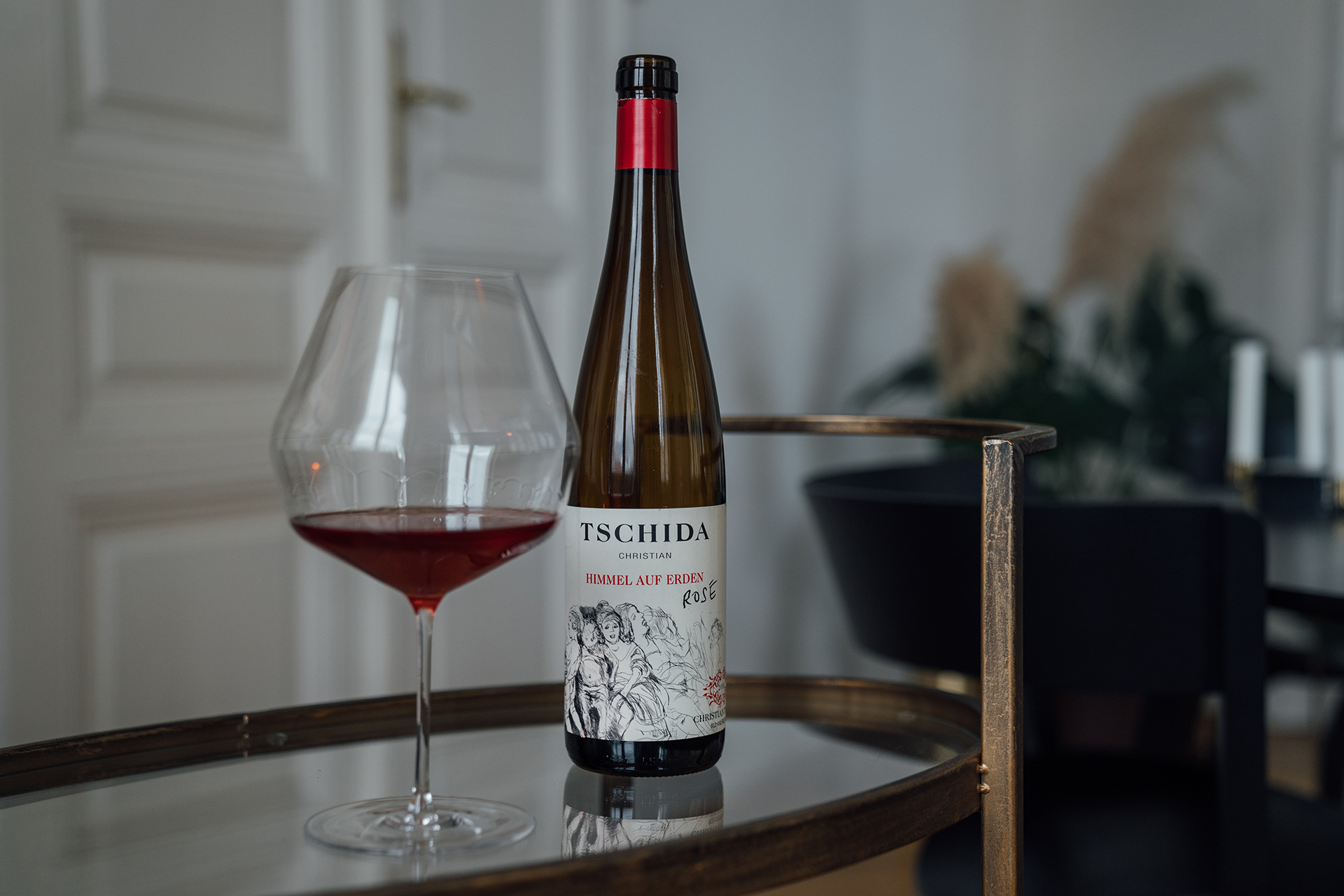 Eine geöffnete Flasche "Himmel auf Erden Rosé" von Christian Tschida, daneben ein gefülltes Burgunderglas.